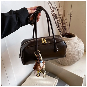 Detail of a dark brown glossy leather Boston bag with a vintage charm and plush charm