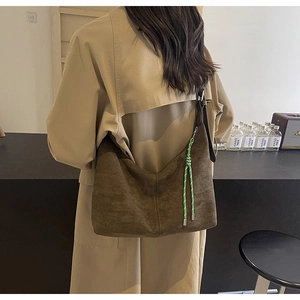 Close-up of brown suede hobo bag with a contrasting green woven strap accessory