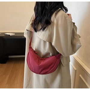 Detail showing the burgundy nylon crescent bag with adjustable wide strap on model