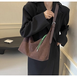 Detail of dark brown suede hobo bag with adjustable strap and green woven lanyard accent