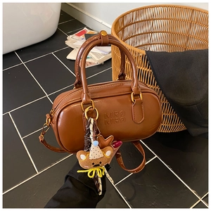 Détail du sac boston en cuir caramel avec logo Mira Mira et charm ours mignon