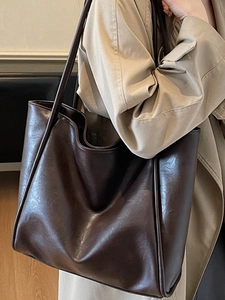 Minimalist large brown leather tote bag for women commuting, shown on model with trench coat