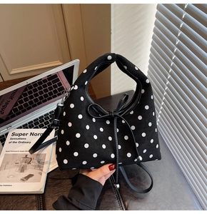 Détail d'un sac à main chic à pois noirs avec un nœud en cuir et des détails argentés