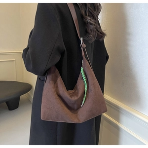 Close-up of vintage brown suede tote bag with a bright green woven rope charm detail