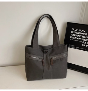 Macro view of dark grey canvas tote with metal zippers and premium texture details