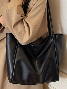Minimalist black leather tote bag for women featuring a large capacity and slim shoulder straps