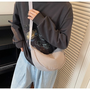 Detailed view of the beige crescent crossbody bag with an adjustable wide fabric strap