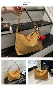 Detail einer braunen Wildleder-Hobo-Tasche mit Holzperlen und rotem Bommel-Anhänger