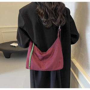 Detail of burgundy suede tote bag featuring contrasting green braided rope decoration