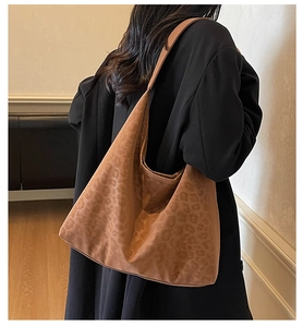 Close-up of brown leopard print hobo bag in suede texture worn on shoulder