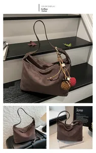 Detailansicht der kaffeebraunen Hobo-Bag aus Wildleder mit verstellbarem Riemen und Pompon