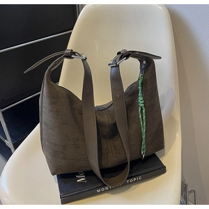 Detail of suede charcoal brown tote bag featuring contrast stitching and green tassel