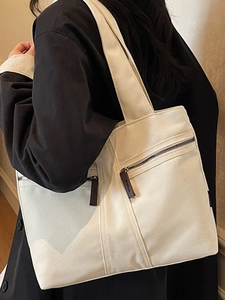 Minimalist beige canvas tote bag with dual front zipper pockets for commuting
