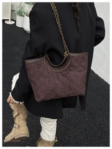 Quilted tote bag with gold chain strap shown in a lifestyle outdoor street view