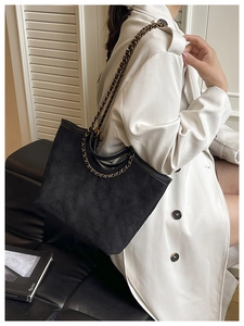 Detailed view of black quilted tote bag with chain strap and soft suede texture