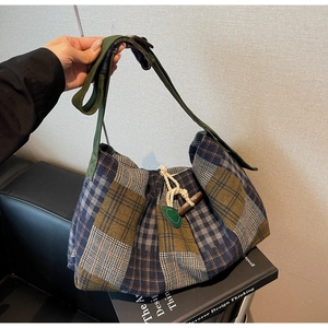 Detailed close-up of large plaid wool tote bag with toggle closure and woven strap