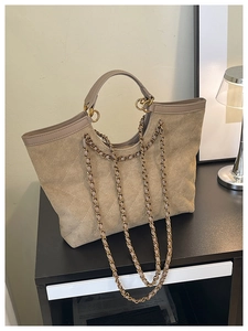 Detail of khaki suede tote bag featuring quilted diamond patterns and metal chain strap