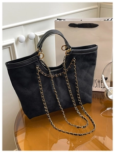 Detailed close-up of quilted pattern on black suede tote bag with metal chain strap