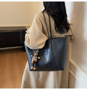 Detail of black large tote bag with textured faux leather and a cute bunny charm