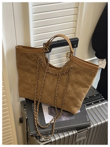 Close-up of brown suede tote bag with quilted diamond pattern and gold chain straps