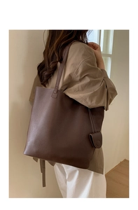 Deep brown bucket bag with lychee texture featuring a mini pouch charm and slim strap