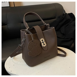 Close-up of coffee brown lychee grain leather bucket bag with dog charm and metal lock