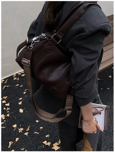 Detail of dark brown tote bag with woven bohemian strap and textured faux leather finish