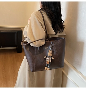 Detailed view of large brown vintage leather tote bag with a plush bunny charm