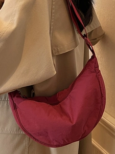 Minimalist burgundy nylon crescent crossbody bag styled with a khaki trench coat for women