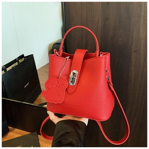 Detail of red litchi grain bucket bag with silver hardware and a cute puppy leather charm