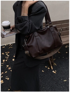 Detail of vintage dark brown faux leather tote bag with wide strap and silver hardware