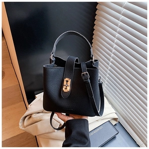 Detail of black lychee grain leather bucket bag with elegant golden twist lock closure