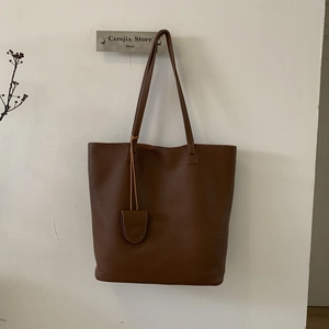 Minimalist deep brown lychee grain bucket bag with slim shoulder straps and round charm
