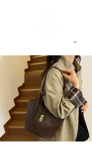 Detail of a dark brown matte leather tote bag featuring a gold square metal clasp closure