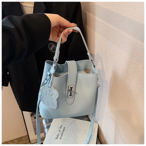 Detail of light blue lychee pattern bucket bag with metal lock and cute puppy charm