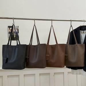 Minimalist leather tote bags in black, coffee, brown, and taupe displayed on a rack