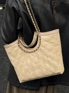 Quilted beige suede tote bag with metal chain strap for women shown on shoulder