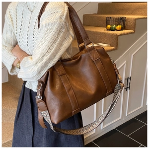 Detail of a brown leather tote with jacquard strap and silver metallic hardware