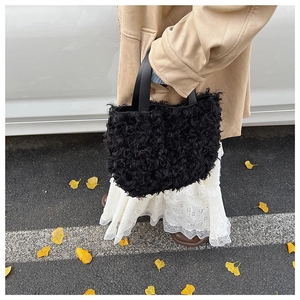 Detail of black faux fur bucket bag held by a model on a scenic autumn street