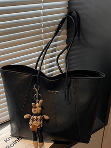 Large black PU leather tote bag with rabbit pendant and brand print in minimalist studio
