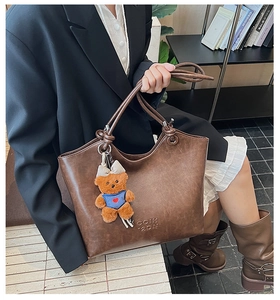 Close-up of brown vintage tote bag with retro leather texture and cute bear pendant