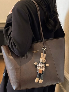 Large dark brown leather tote bag with vintage texture and cute plush bunny charm