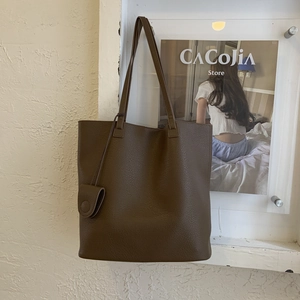 Detail of dark brown tote bag with pebble leather texture and small hanging pouch