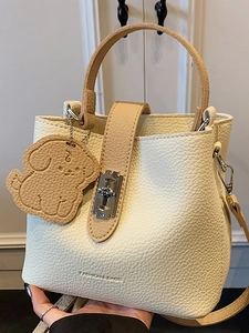 Minimalist white litchi leather bucket bag with dog pendant and crossbody strap