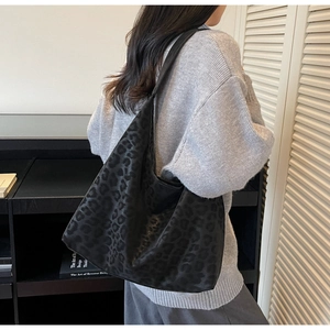 Detail of a large matte black leopard print tote bag with soft suede texture and wide strap