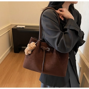 Detail of vintage brown suede tote bag with metal buckle and plush bear pendant