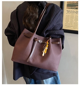 Brown vintage leather tote bag with stylish beaded pendant and minimalist shoulder strap