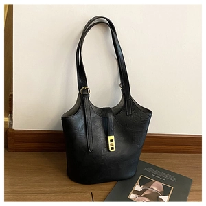 Detail of black leather tote bag featuring subtle wrinkled texture and gold metal buckle