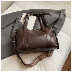 Detail view of coffee brown Boston bag with bohemian woven shoulder strap and PU leather texture