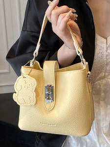 Minimalist light yellow lychee pattern bucket bag with metal lock and dog charm